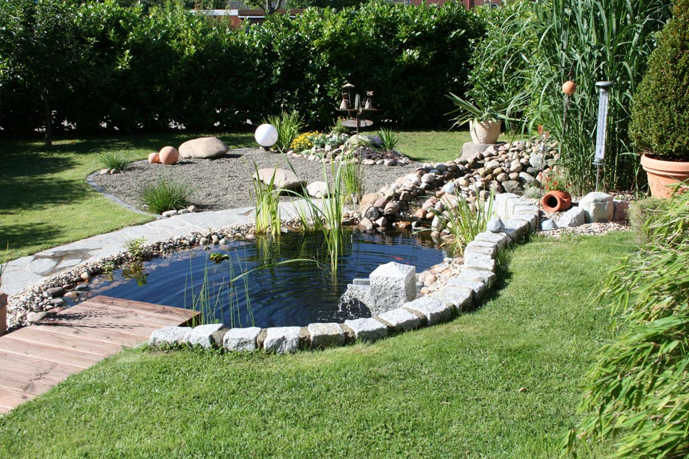Garten mit Natursteinen - mit Mauersteinen eingefasster Teich. Vorplatz mit getrommeltem Edelsplitt